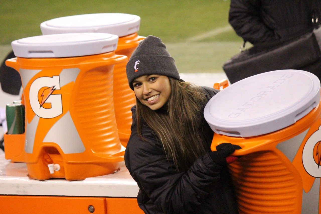 Bryn Cortez, 3rd year  in the Health Science - Pre Athletic Training Program, holds water on the football field.