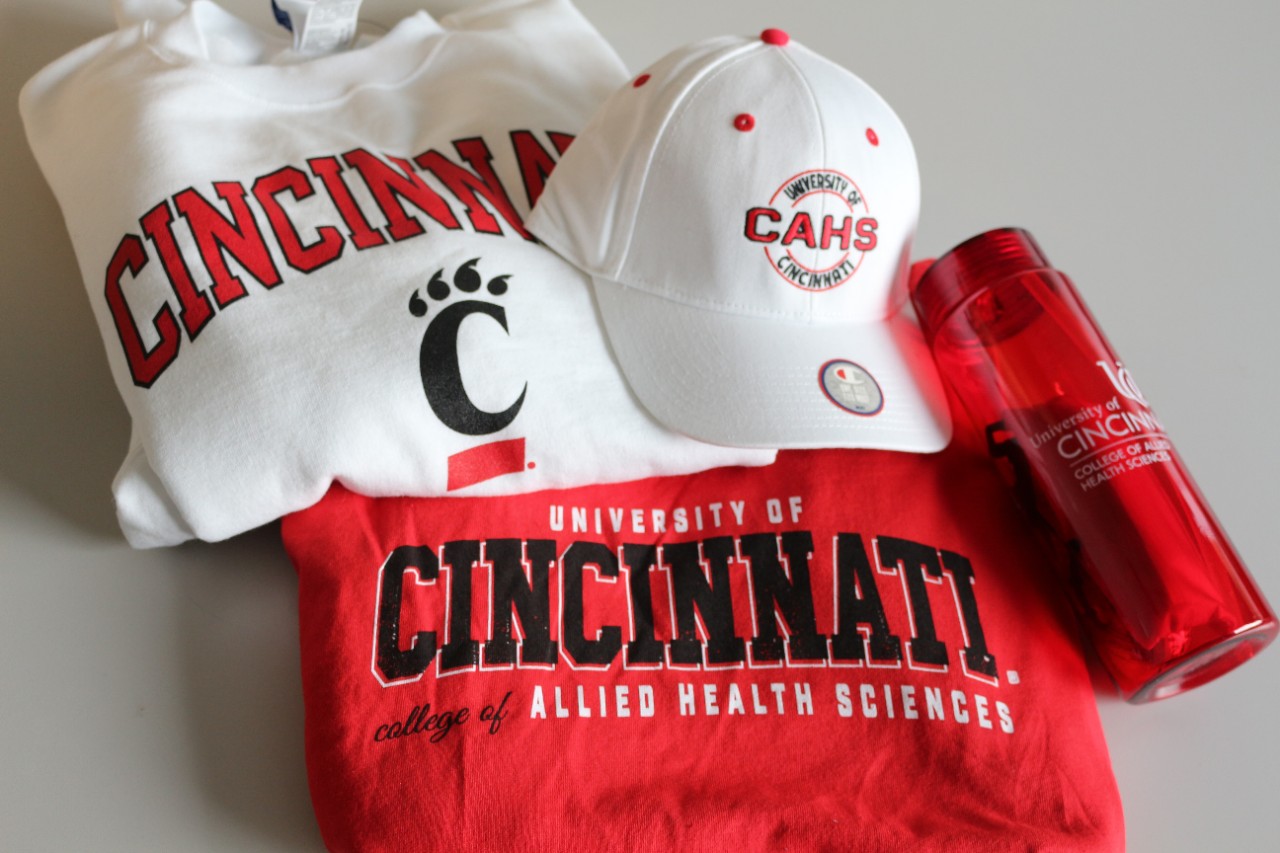 a white UC sweatshirt, A white CAHS hat, a red CAHS T-shirt, and a red CAHS water bottle 