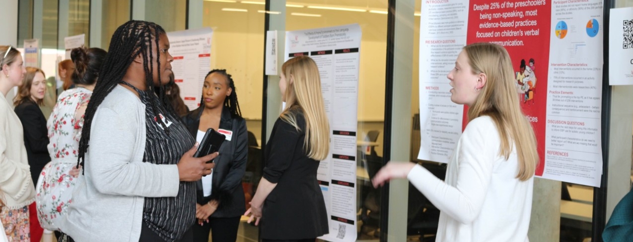 Student explaining research on her poster to a community member