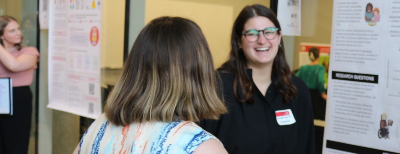 Student happily explains research to faculty member.
